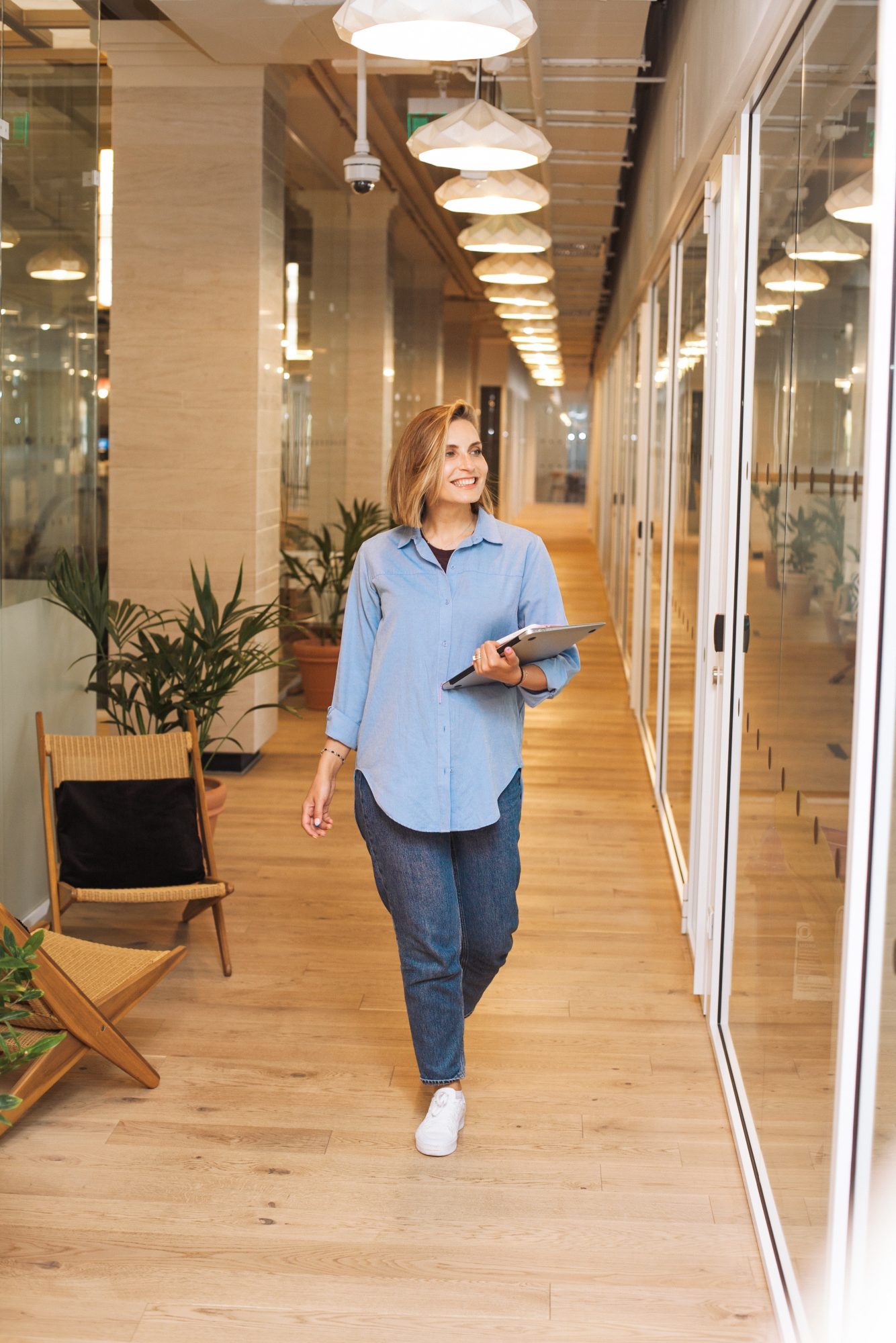 Consultante tech marchant dans un couloir de bureaux, tablette en main